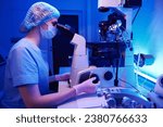 Serious embryologist is carrying out ICSI with micromanipulator in laboratory