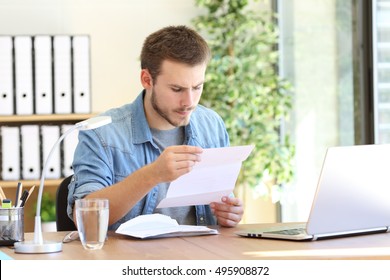 Serious entrepreneur working and reading a letter in a desktop at workplace