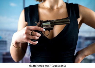 Serious Faceless Woman In A Stylish Dress Holds A Revolver For A Shot Against The Background Of Office Windows. Woman Killer Shooting. Office Robbery