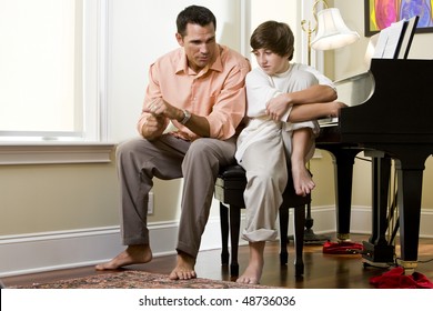 Serious Father Talking To Teenage Son At Home By Piano