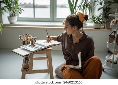 Serious female artist painting with watercolors. Thorough scrupulous woman learning studying basics of working with watercolors training developing skill of drawing using brushes, aquarelle.