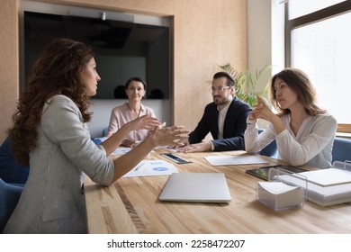 Serious female business partners talking at meeting table, discussing deal, startup buying issues, contract, investment terms. Group of business people negotiating in office boardroom - Powered by Shutterstock