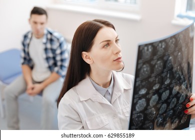 Serious female neurologist examining the X ray photo