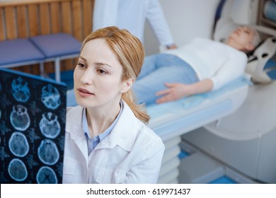 Serious Female Oncologist Examining Results Of The CT Scan