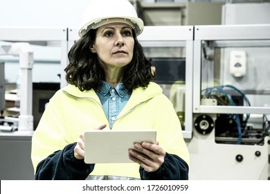 Serious Female Technician Holding Tablet. Confident Factory Worker Using Tablet While Standing Near Printing Machine. Print Manufacturing, Technology Concept