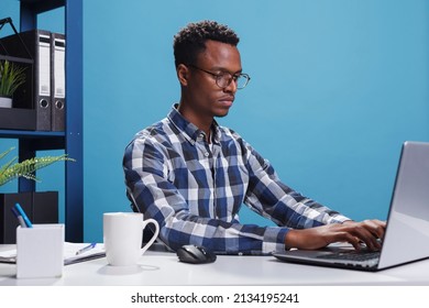 Serious Firm Project Manager Sitting At Desk In Modern Office While Using Laptop To Develop Marketing Strategy. Confident Company Employee Using Work Computer To Analyze Accounting Documentation.