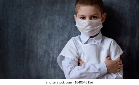 A serious, focused boy in a medical mask and a white coat, stands against the background of a black slate board. Playing doctor, future profession. Pediatrics, healthcare and people concept. - Powered by Shutterstock