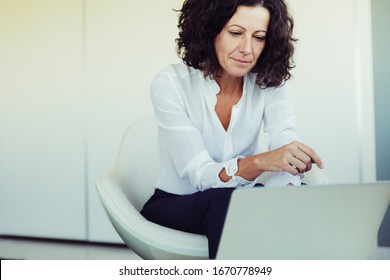 Serious Focused Business Lady Working On Computer In Office Lounge. Business Woman Sitting In Armchair, Using Laptop, Looking At Screen. Communication Concept