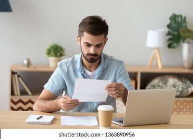 Serious focused businessman, freelancer attentively reading paper document, unpleasant news, received letter, analyzing offer, financial report with project statistics, notification - Powered by Shutterstock