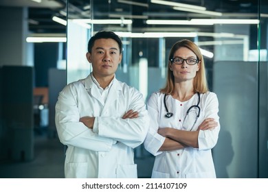 Serious And Focused Doctors With Arms Crossed Looking At Camera, Asian Man And Woman Team Working In Clinic