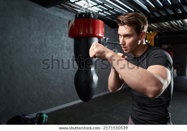 Serious focused\
male boxer shadow-boxing at\
gym