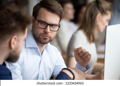 Serious Focused Male Employee In Glasses Attentively Listening To Colleague, Looking At Boss, Director, Receiving Notes, Criticism, Thinking About Business Strategy Close Up