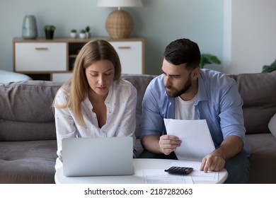 Serious Focused Millennial Couple Analyzing Household Budget, Calculate Expenses Sit On Sofa At Table With Laptop, Pay Bills Or Taxes On-line Use Computer. Finances Management, Loan Payments Concept