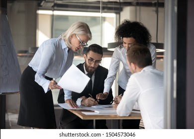 Serious focused multi-ethnic team working together do paperwork lawyer and command reviewing contract details, financiers analyzing financial statistics work results, teamwork group meeting concept - Powered by Shutterstock