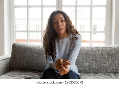 Serious friendly african woman internet teacher tutor looking at camera talking, black mixed race millennial female vlogger speaking making video call vlog, online job interview at home, portrait