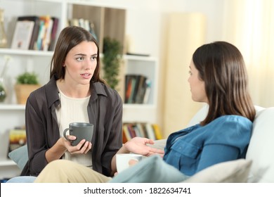 Serious Friends Talking Sitting On A Couch In The Living Room At Home 