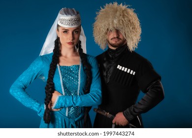 Serious Georgian Newlyweds Couple Posing On Blue Backdrop. High Quality Picture Of Authentic Caucasian Dancers Performing On Dark Blue Matte Background