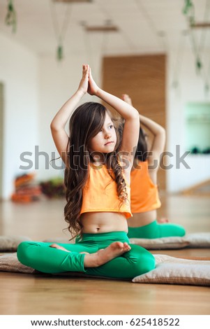 Serious girl child practicing yoga, indoor full length, white loft studio background
