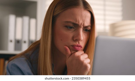 Serious girl frown puzzled stressed Caucasian woman looking at computer monitor problem business failure bad news thinking pensive thoughtful solving web problem businesswoman look at laptop screen