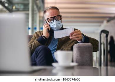 Serious gray-haired male tourist with a boarding pass in his hand making a phone call - Powered by Shutterstock