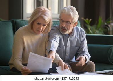 Serious Grey Haired Mature Couple Calculating Bills, Checking Finances Together At Home, Senior Retired Old Family Reading Documents, Insurance Paper, Worried About Loan, Bankruptcy Or Money Problem