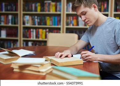 Serious guy rewriting information from book into his copybook