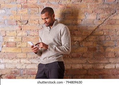A serious handsome young man using his smartphone in a sweater.