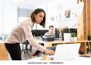 Serious Hispanic Woman Spying The Laptop Of Her Coworker In The Office.