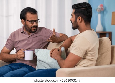 Serious indian father discussing with son while having coffee at home - concept of Parental Advice, family Mentorship and sharing Life Lessons - Powered by Shutterstock