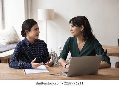 Serious Indian mentor or teacher talk to female colleague teach intern, discussing new project or task sit at desk in office. Two diverse coworkers working together, cooperate, engaged in team-work - Shutterstock ID 2289776211