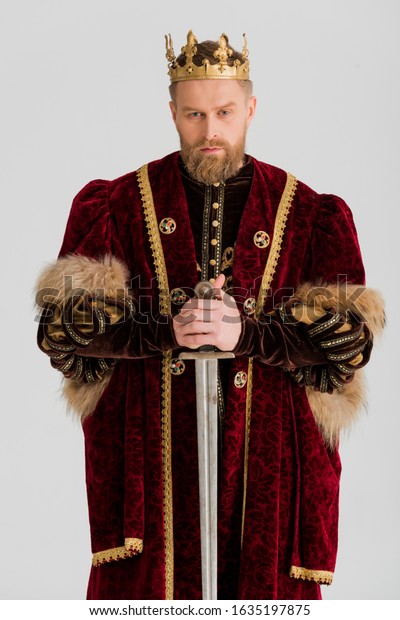 serious\
king with crown holding sword isolated on\
grey