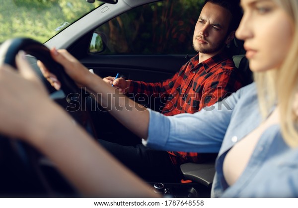 Serious lady\
and instructor in car, driving\
school
