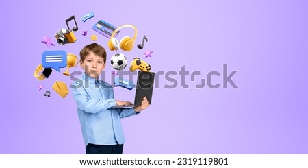 Serious little boy kid holding laptop standing over purple background with online entertainment and gaming icons around him. Concept of modern technology. Copy space