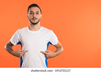 Serious looking Football fan or player pointing with fingers at invisible t-shirt logo, copy space - Powered by Shutterstock