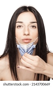 Serious Looking Girl Pulling Away Medical Face Mask. Portrait Against White Background.