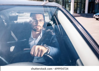 Serious Looking Man In Glasses Seating In Black Car