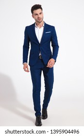 Serious Looking Man Walking Forward And Staring To The Side While Wearing A Blue Suit On White Studio Background