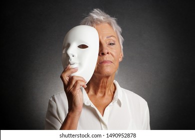 Serious Looking Older Woman Revealing True Face Behind Mask