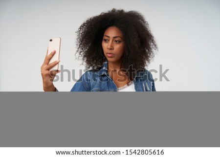 Similar – Serious black woman with afro hair looking at her smart phone outdoors.