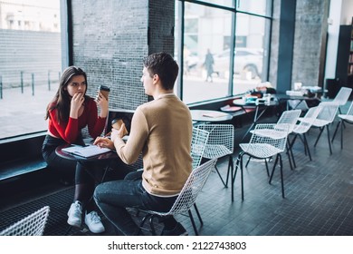 Serious Male And Female College Students In Casual Clothes Having Coffee Break In Empty Cafeteria After Working On Project Together