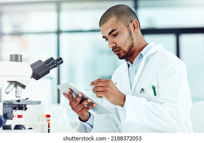 Serious Male Scientist Working On A Tablet Reviewing An Online Phd Publication In A Lab. Laboratory Worker Updating Health Data For A Science Journal. Medical Professional Document Clinical Trial