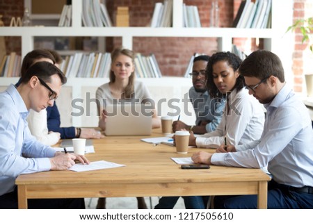 Serious male workers sign business contracts during corporate meeting with colleagues, hired employees put signature on document finalizing recruitment, men filling in paperwork at office briefing