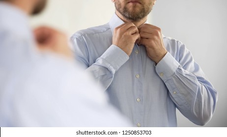 Serious Man Buttoning His Shirt In Optimistic Mood, Getting Ready For Work