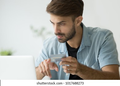 Serious man buying shopping paying online with credit card and laptop, young guy making internet purchase using web banking service looking at computer screen, customer consumer making secure payment