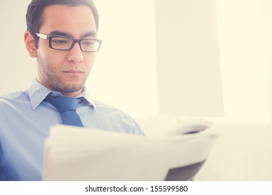 Serious Man With Glasses Reading A Newspaper 