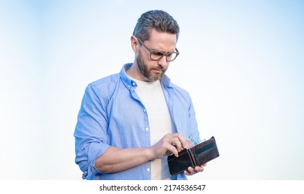 Serious man in glasses taking cash money out of wallet sky background