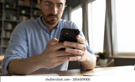 Serious Man Manager Using Smartphone Chat With Client Sit At Desk In Office, Close Up Focus On Hands Hold Modern Gadget. Online Communication, Business Question Solution, E-business App Usage Concept