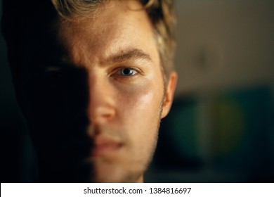 Serious Man Portrait In Light On Dark Background. Closeup Of Man Face With Blue Eyes And Blonde Hair In Softlight. Selective Focus. Creative Image