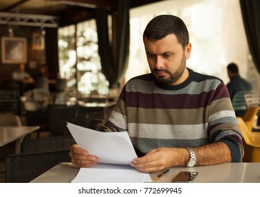 Serious Man Reading Document In Cafe