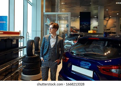 Serious Man Standing Next To Cars In A Dealership And Looking At The Camera. Close Up Photo. Copy Space. Guy Thinking To Buy A Cra Or Not